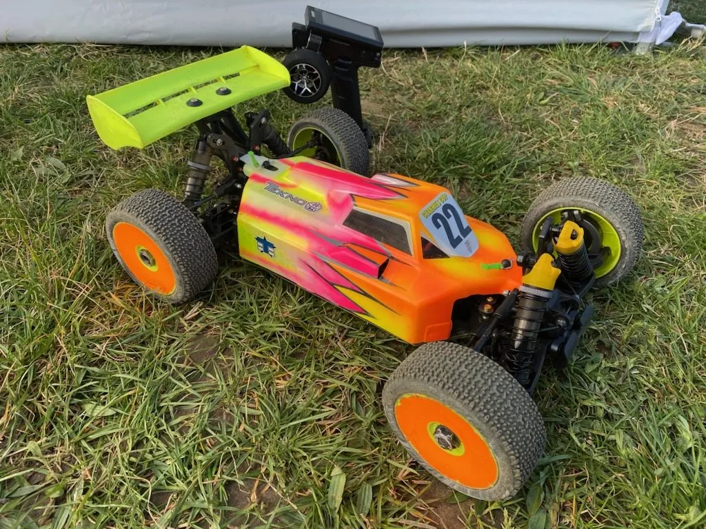 Buggy Tekno 1/8 équipé de pièces JSN Concept, posé dans l'herbe au bord de la piste